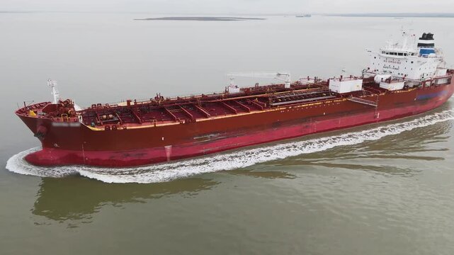 red tanker ship named gliding smoothly through calm grey waters steel deck lined pipelines cargo systems long aerial view oil fuel gas crisis sea gulf qatar iran war 