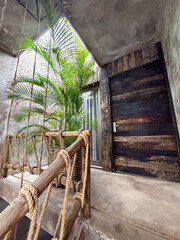 Fototapeta premium Indoor balcony with rope railing, lush palm and wooden door, low angle view