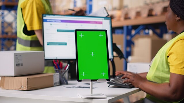 Warehouse employee in hi vis vest uses copy space display with technology of shipping software, packaging systems and inventory management tools. E-commerce logistics. Camera B.