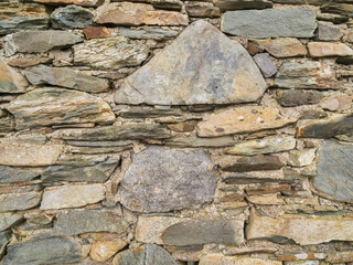 Fototapeta premium Rugged stone wall shows ancient craftsmanship. Weathered rocks lie stacked with care. Each stone tells a story of time. Surface bears signs of wind and rain. Perfect for rustic, historical theme.