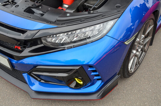 Close-up of a blue Honda Civic Type R front end, featuring a sharp LED headlight and red "R" badge
