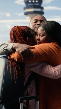Vertical Video Heartfelt airport send-off with mother and father hugging girl before leaving for university abroad. Solo traveler with luggage prepares for boarding on the plane, emotional farewell in