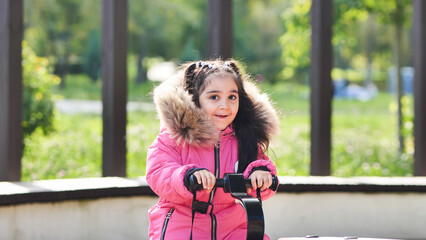 Young girl smiling outdoors, enjoying playtime in a warm pink winter parka © Довидович Михаил