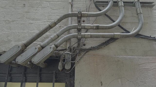 Looking Up at Brick Building with Galvanized Conduits in Rain