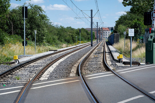Perspective view of a railroad crossing with double tracks, overhead power lines, and signaling equipment in the Weidenpesch district of Cologne