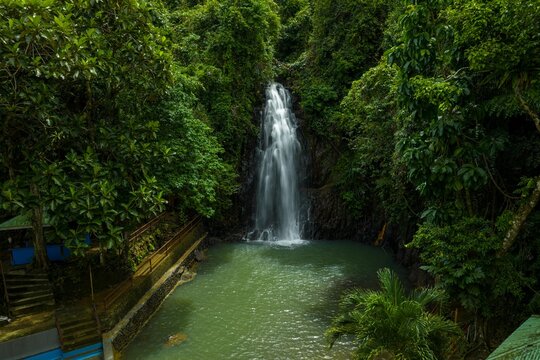 Aerial view of Taktak Falls in Santa Monica, Siargao. The island's unique waterfall cascading into a natural pool within a lush tropical rainforest, Philippines.