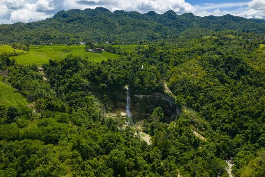 Aerial view of Cadapdapan Rice Terraces and Can-umantad Falls in Candijay, Bohol. Lush green agricultural landscape and majestic waterfall, Philippines