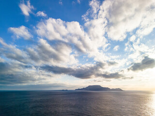 Obraz premium 沖に神津島が見える。 青い海と緑の森が美しい、式根島の空中ドローン撮影。 東京都伊豆諸島式根島-2025式根島は東京都心から南へ160km。 外周12kmの小さな有人島。 温かい黒潮が当たり水温と水質が高い。 また、リアス式の入り組んだ入り江が多く、海水浴や釣りが盛ん。 温泉島としても有名。海際に多くの無料露天風呂がある。 