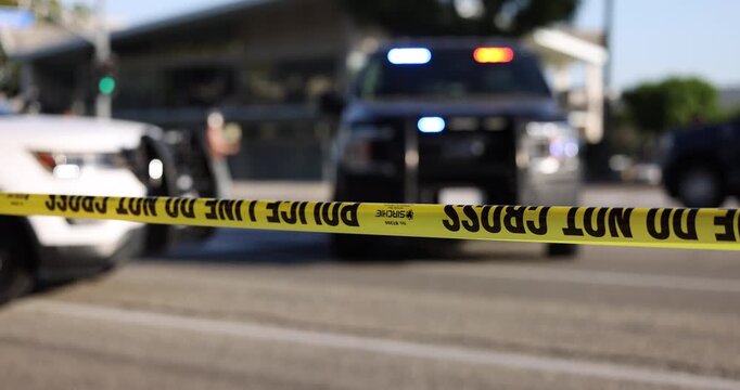 Daytime abstracted view of cordon tape and police units responding to an emergency.