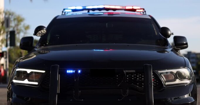 Medium tight side view of flashing blue lights on top of a police car.
