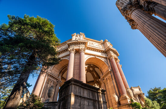 A dramatic low-angle perspective showcases the towering Greco-Roman columns and intricate rotunda of the Palace of Fine Arts against a brilliant blue San Francisco sky.