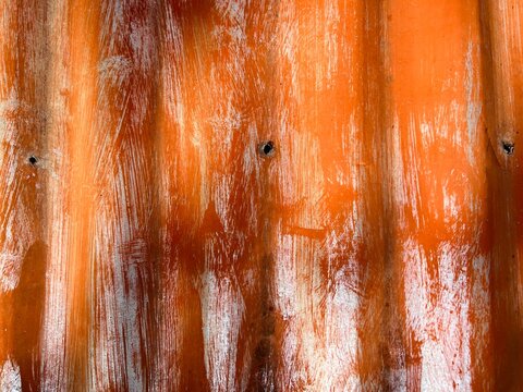 Weathered orange corrugated metal sheet with white paint scuffs and rustic texture.