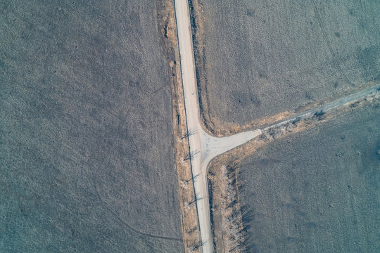Rural road intersection T-junction in a desolate winter field, transport logistics and terrain mapping, aerial drone perspective