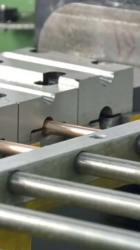 Gleaming copper pipeline undergoes transformation in automated factory. Powerful machinery expertly forms and shapes raw metal material with impressive precision and rhythm, ensuring quality results.