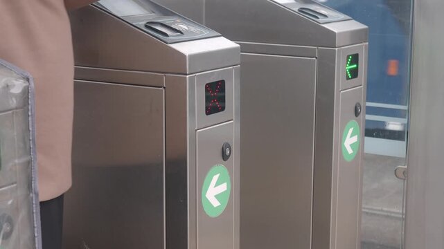 Woman attempts to pass through subway turnstile with bag only to have it deny entry and then try again successfully