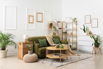 Fototapeta premium Interior of light living room with green sofa, shelf unit and plants