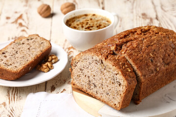 Fototapeta premium Board with delicious walnut loaf cake and cup of coffee on wooden background