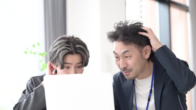 パソコンの画面を見ながらビックリして驚く悩むビジネスマン2人　これってヤバイ！トラブルに焦る上司と若手社員の問題発生ビジネスシーンの動画