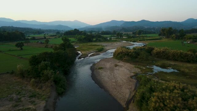 Aerial 4K of a peaceful river winding through the valley at sunset, Pai, Thailand