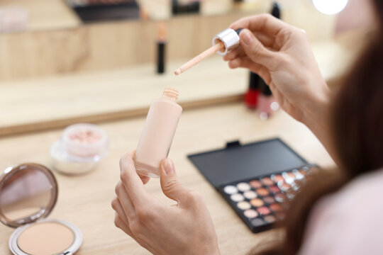 Woman with bottle of foundation at table, closeup