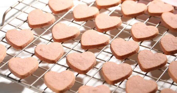 Tasty heart shaped oatmeal cookies on cooling rack at white table, closeup