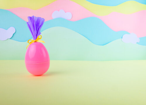 Pink easter egg wrapped as gift on pastel landscape background with clouds festive spring decoration concept. Pastel.