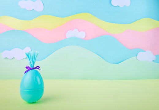 Modern minimal easter background with single wrapped egg in pastel colors with clouds and large copy space for design. Egg blue.