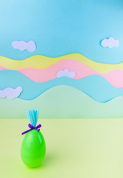 Cute greeneaster egg with bow and wrapping on soft pastel background with clouds spring holiday minimal banner with copy space
