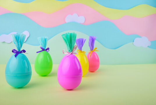Cute colorful easter eggs with bows and wrapping on soft pastel background with clouds spring celebration holiday concept for kids.