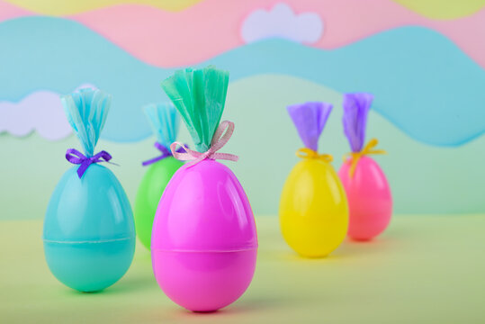 Multicolored easter eggs arranged in row with gift wrapping on pastel background with clouds festive spring decoration concept.