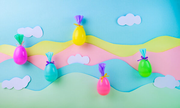 Floating colorful easter eggs with gift wrapping on pastel rainbow background with clouds spring holiday decoration concept with copy space.