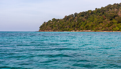 Fototapeta premium Koh Adang coastline in Tarutao National Park. Tropical island with lush greenery. Turquoise waters of the Andaman Sea.