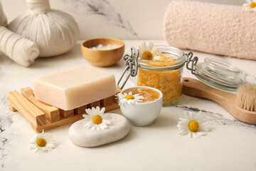 Chamomile flowers, glass jar with sea salt and bowl with honey on marble background, closeup