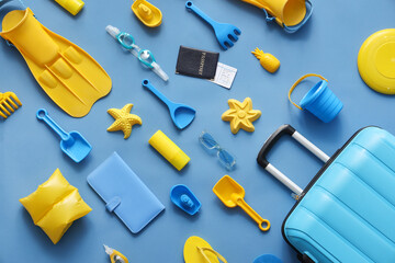 Summer composition with suitcase, beach toys, flippers and passport on blue background © Pixel-Shot
