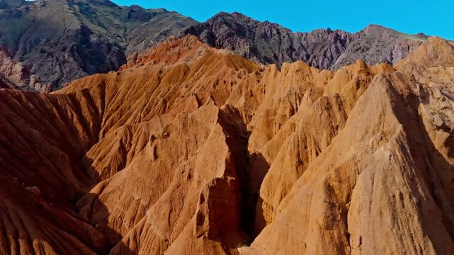 Majestic eroded sandstone formations rise in Konorchek canyons, Kyrgyzstan. Drone view captures stunning geological landscapes under bright daytime sky.