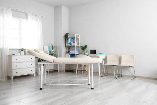 Interior of medical cabinet with shelving units, couch and laptop on workplace