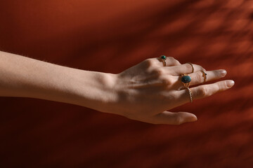 Female hand with beautiful rings on orange background