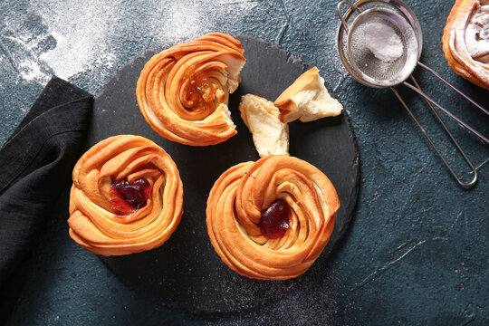 Board of tasty cruffins with jam on black background
