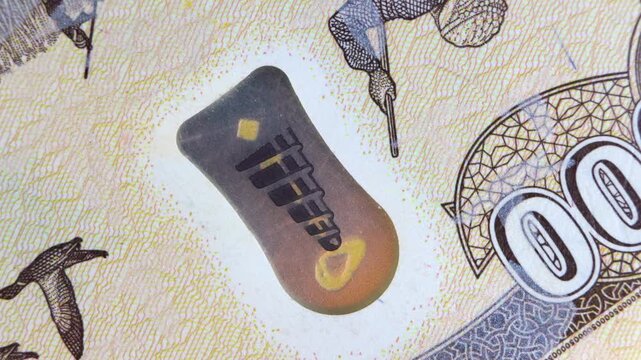 Macro of the 50000 Iraqi Dinar banknote featuring a color-shifting "SPARK Live" lantern icon. The shot showcases intricate printing, a falconer illustration, and gold-to-green holographic security ink