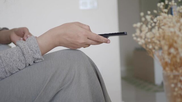 Close up of hand holding remote control changing channels on television at home