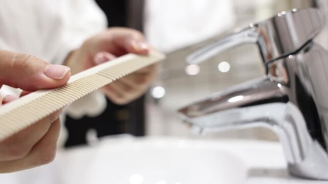 close up of person unpacking fine tooth comb near sink hygiene and personal care concept bathroom interior