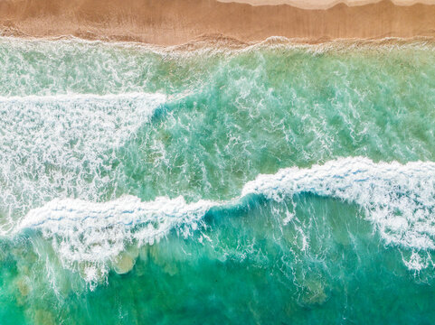 aerial drone view of waves crashing on beach