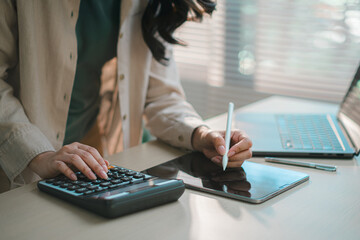 businesswoman using calculator on desk, representing digital finance, accounting, online banking, budgeting, tax management and modern fintech