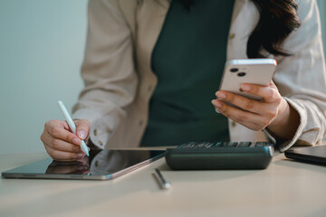 businesswoman using smartphone and tablet with calculator on desk, representing digital finance, accounting, online banking, budgeting, tax management and modern fintech workflow in office