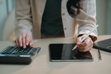 businesswoman using tablet with calculator on desk, representing digital finance, accounting, online banking, budgeting, tax management and modern fintech workflow in office