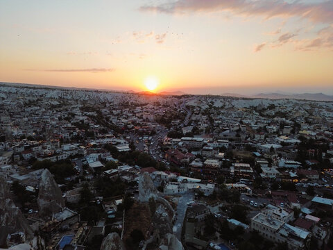 Aerial drone video of Cappadocia city at sunset, Turkey. Beautiful landscape with traditional stone houses, unique rock formations, and warm golden light creating a magical atmosphere. Ideal for touri