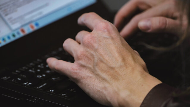 Hands typing on a laptop, performing data entry or programming work in Moscow