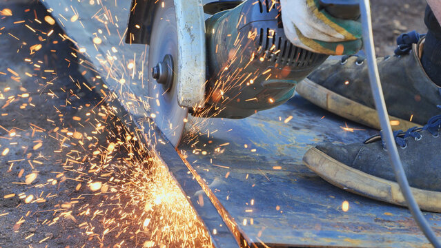Worker cutting metal using an angle grinder, producing sparks in Moscow