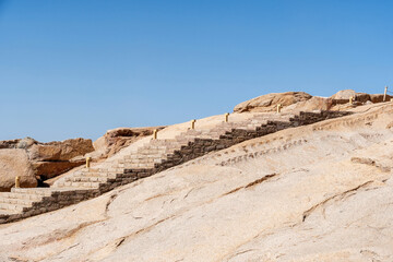 Obraz premium Stone stairs ascend a rugged desert hillside under a clear blue