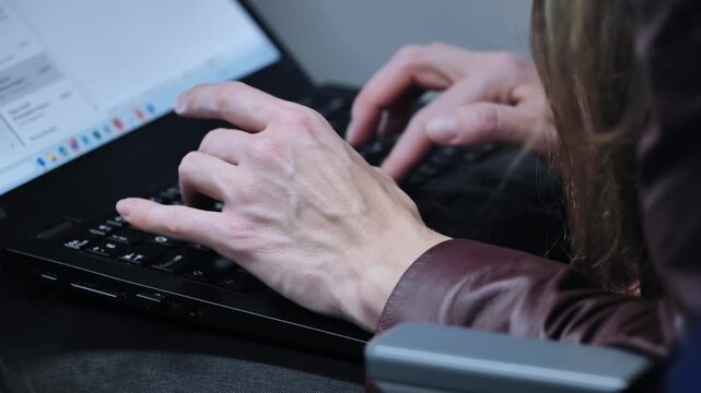 Person working on a laptop, typing on keyboard, remote work
